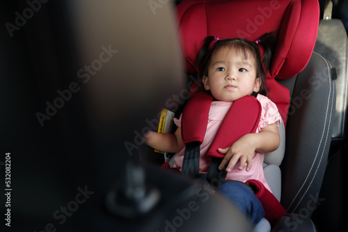 unhappy toddler girl sitting in car seat