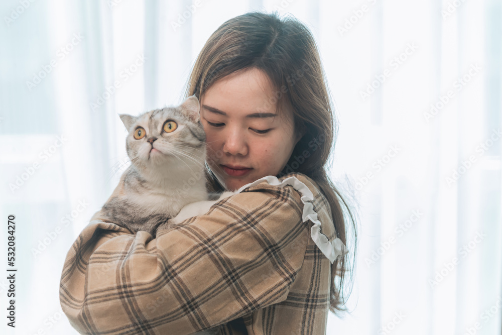 A young woman is holding lovely cat playing with cat