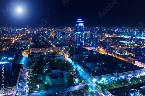 Aerial view of the night modern city. Bright moon and lights of the night streets
