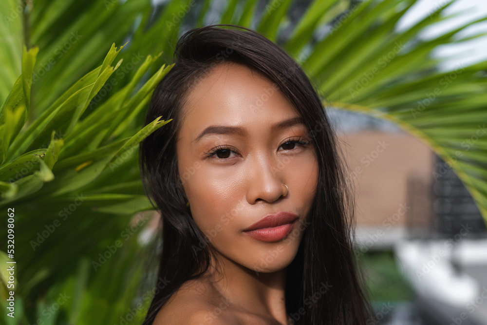 Beautiful asian thai woman with soft smooth clean dark tanned skin beauty portrait skincare positive posing with green leaves plump lips outdoor natural beauty Beautiful asian thai woman with soft smooth clean dark tanned skin beauty portrait skincare positive posing with green leaves plump lips outdoor natural beauty
