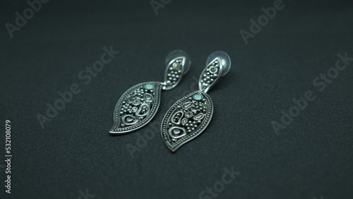 Leaf shaped silver earrings on black background