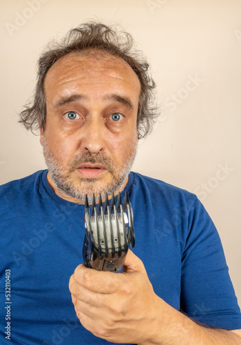 desperate looking man with partially cut hair looks at hair trimmer failed during use