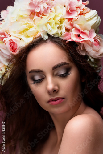 Portrait of a beautiful girl in a delicate wreath of flowers, with long red flowing hair. The concept of perfumery and cosmetics, or beauty salon.