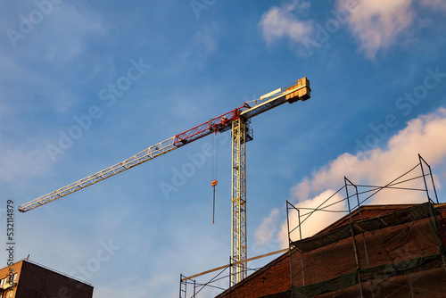 Bottom view of industrial crane. Construction crane work on creation site against blue sky background. Concept of construction of apartment buildings and renovation of housing. Copy space