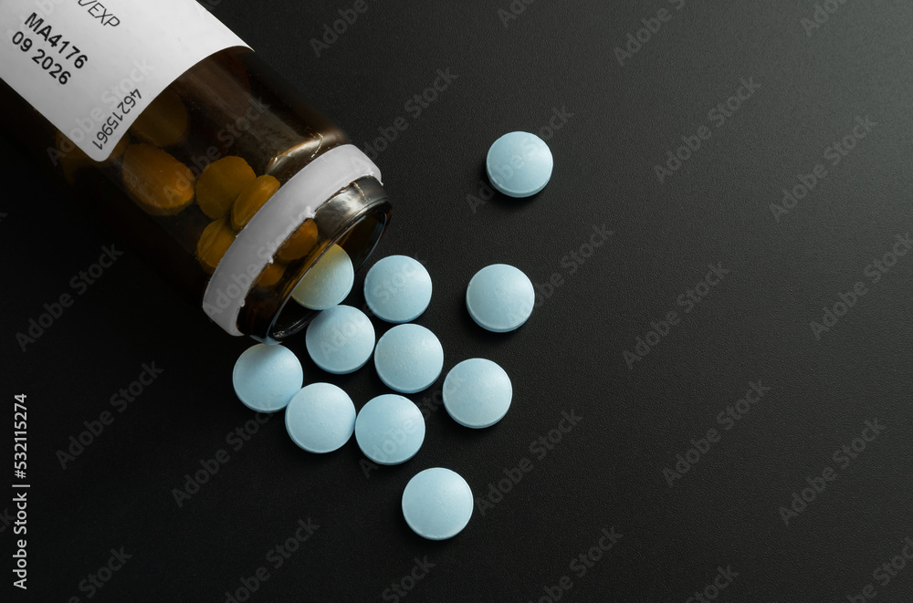 Butelka z rozsypanymi niebieskimi tabletkami leków - obrazy, fototapety, plakaty 