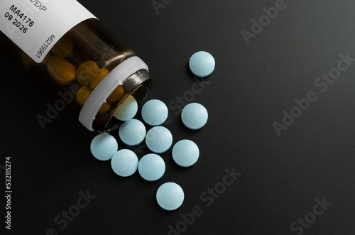 Butelka z rozsypanymi niebieskimi tabletkami leków