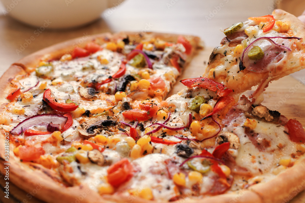 From the pizza lying on a stand on the table, they take another piece. Selective focus. From the pizza lying on a stand on the table, they take another piece. Selective focus.