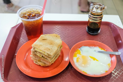 Kaya Toast, slices of toast with butter and kaya, served with ice tea and soft-boiled eggs.