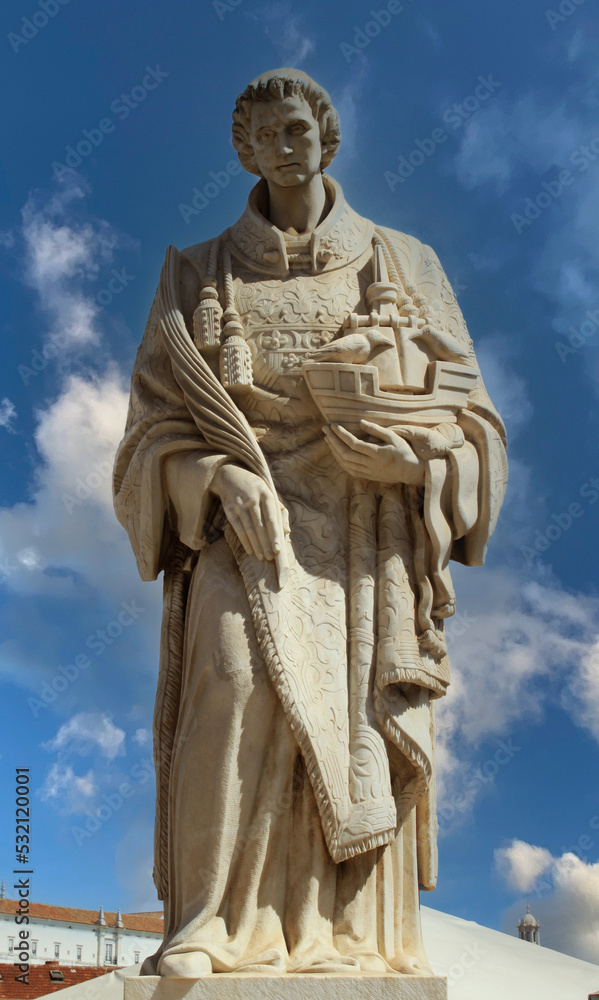 Ancient stone statue of St. Vincent (martyr, patron saint of Lisbon) holding a ship with two crows, the coat of arms of Lisbon in Alfama neighborhood in the old town in Lisbon, Portugal, Europe. 