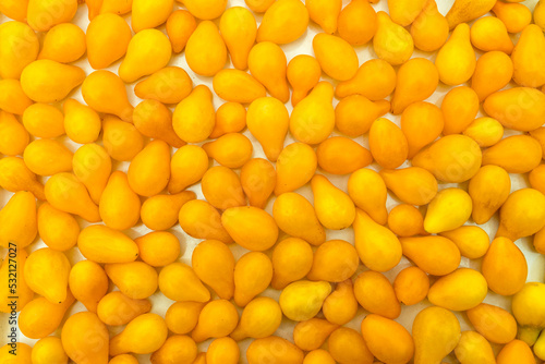 Yellow whole small pear tomatoes close up full frame as background