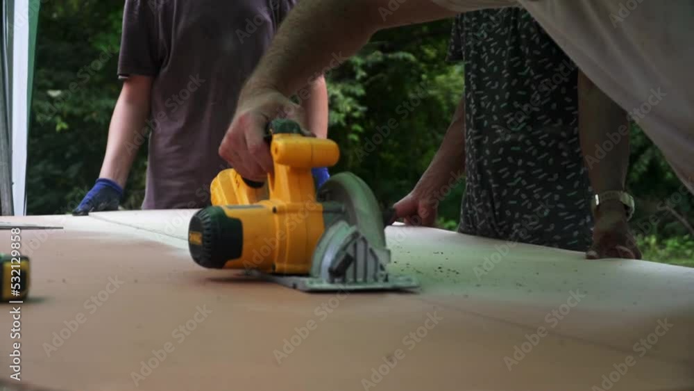 Building contractor worker using hand held worm drive circular saw to cut boards on a new home constructiion project Building contractor worker using hand held worm drive circular saw to cut boards on a new home constructiion project
