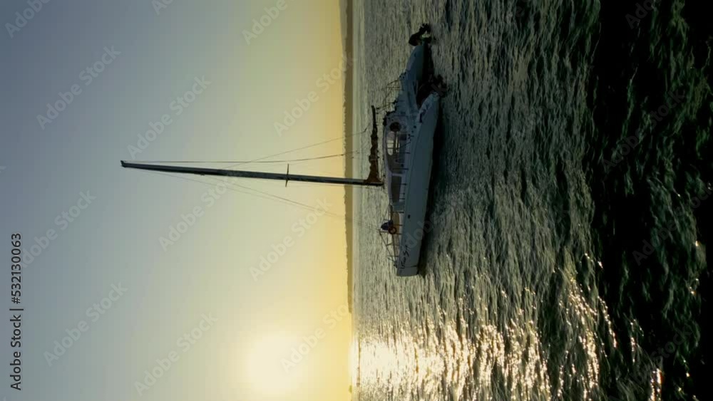 Vertical Shot - Sailing Catamaran Yacht On The Sea With Picturesque Sunrise In The Background. Early Morning At Playa Dorada, Puerto Plata, Dominican Republic. Vertical Shot - Sailing Catamaran Yacht On The Sea With Picturesque Sunrise In The Background. Early Morning At Playa Dorada, Puerto Plata, Dominican Republic.