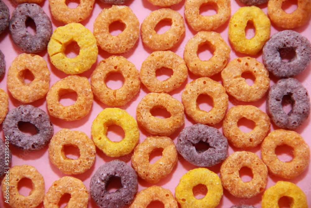 sweet dry children's breakfast multicolored rings close-up on pink background