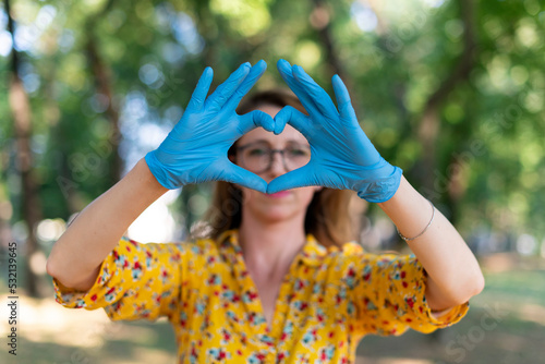 Woman with latex gloves showing heart symbol with hands. Ecology concept