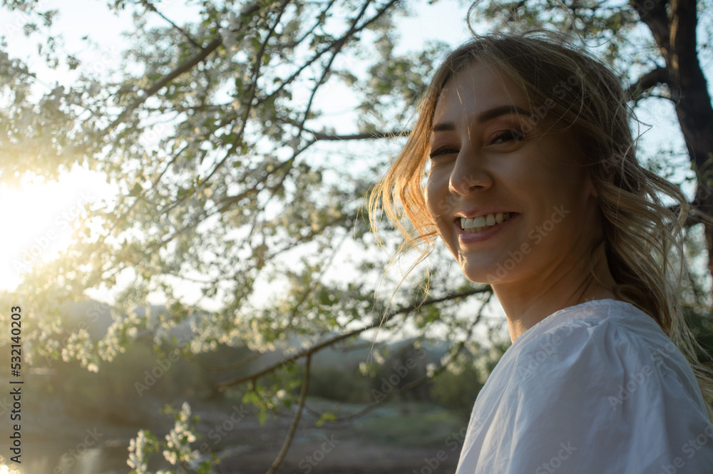 closeup sideview portrait of looking at camera attractive caucasian woman among the flowering apple tree closeup sideview portrait of looking at camera attractive caucasian woman among the flowering apple tree