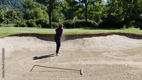 Golfer Hitting the Golf Ball From Sand Trap to Putting Green in a Sunny Day in Lugano, Ticino, Switzerland.
