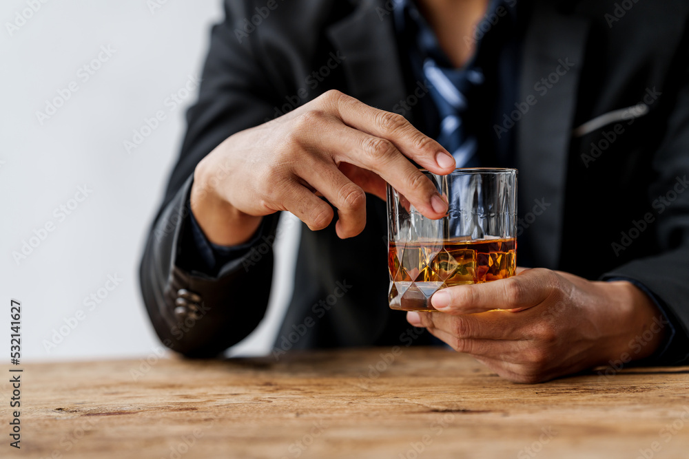 Sad depressed addicted drunk guy, Alone asian man drinker alcoholic sitting at bar counter with glass drinking whiskey.