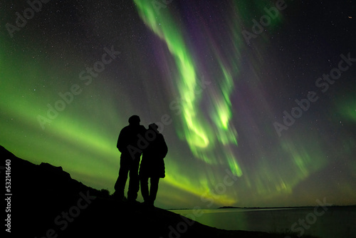silhouette of a couple watching Aurora Borealis