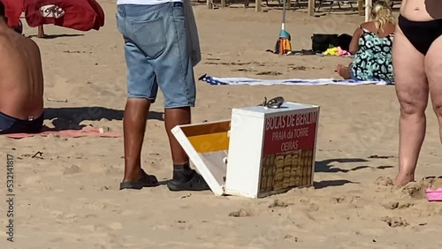 close up of the Berlin Balls (bolas de Berlim) man delivering on beach. Portuguese fried dough with sugar, Filled with sweet cream. Cascais (Praia da Torre) photo