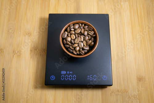 Sixteen gram of roasted coffee beans on a black digital scale
