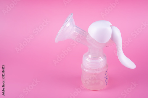 Manual breast pump on pink paper background. Device for increasing milk supply for breastfeeding mother. Maternity and baby care concept photo