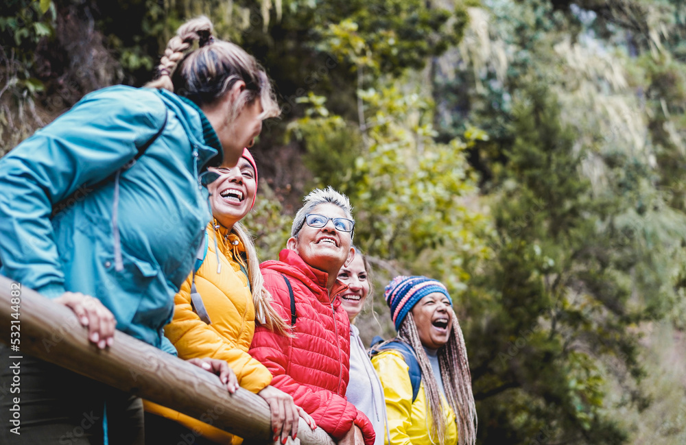 Multiracial women having fun exploring nature on trekking day in mountain forest - Focus on center senior woman face Multiracial women having fun exploring nature on trekking day in mountain forest - Focus on center senior woman face