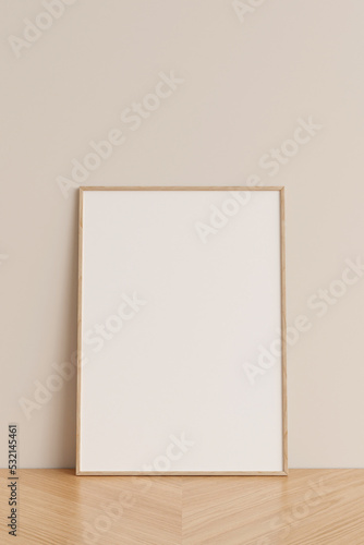 Clean and minimalist front view vertical wooden photo or poster frame mockup leaning against wall on wooden floor. 3d rendering.