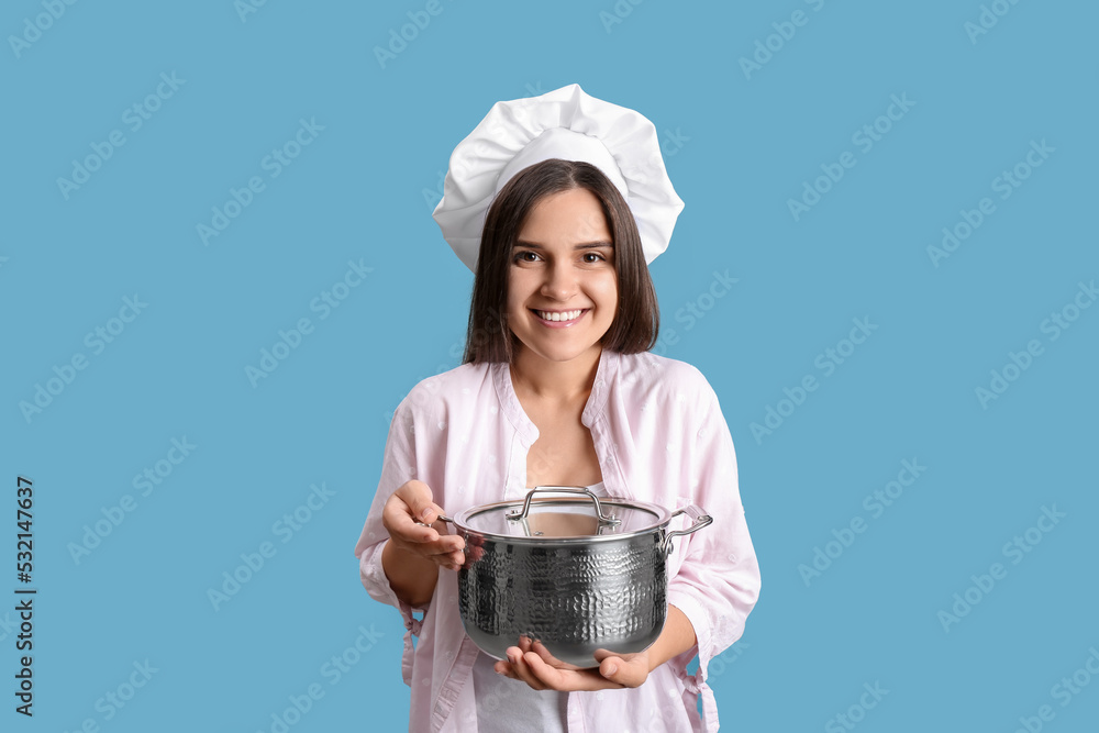 Happy young woman with cooking pot on light blue background Happy young woman with cooking pot on light blue background