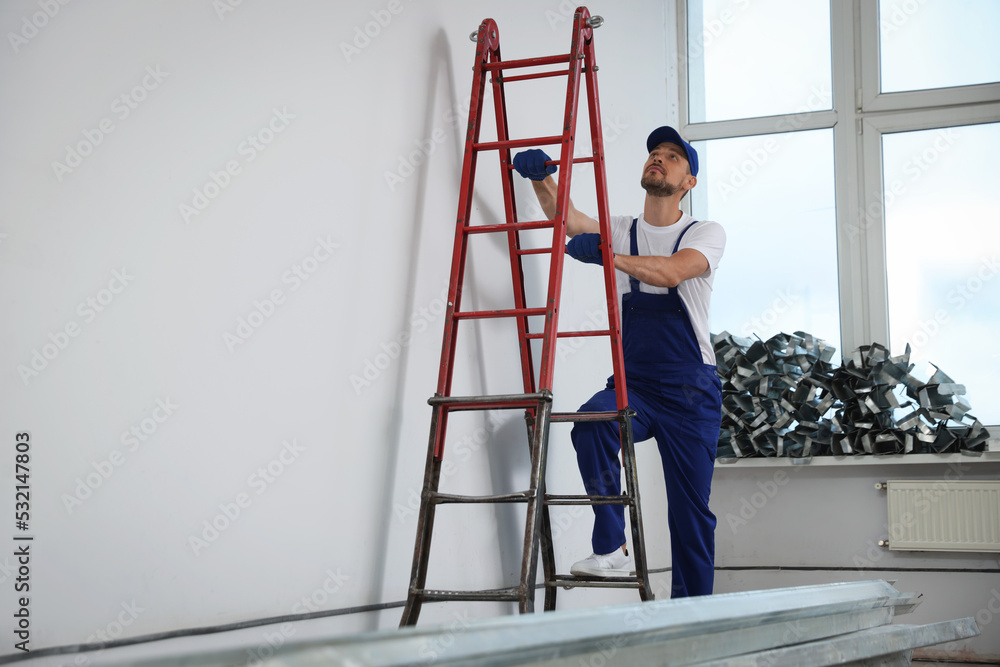 Construction worker climbing up stepladder in room prepared for renovation