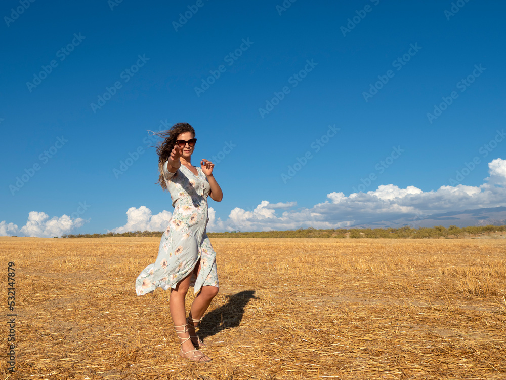 Happy woman in dress outstretching arm at camera in field Happy woman in dress outstretching arm at camera in field