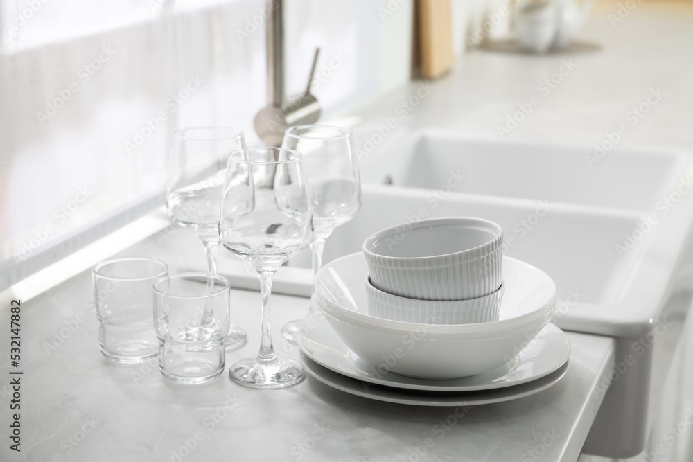Different clean dishware and glasses on countertop near sink in kitchen Different clean dishware and glasses on countertop near sink in kitchen