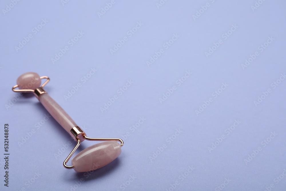 Natural face roller on lilac background. Space for text Natural face roller on lilac background. Space for text