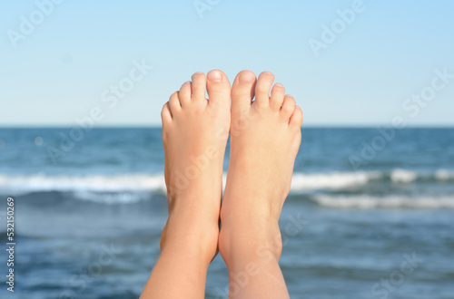 Child resting near sea, closeup of feet