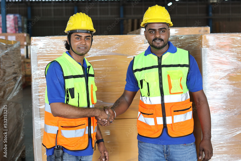 Happy smiling teamwork in hardhats and reflective jackets shaking hands celebrate successful together completed deal commitment at retail warehouse logistics, distribution center, success concept Happy smiling teamwork in hardhats and reflective jackets shaking hands celebrate successful together completed deal commitment at retail warehouse logistics, distribution center, success concept