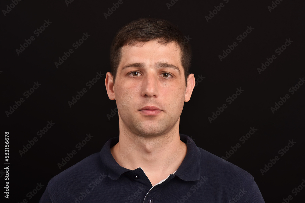 Portrait of young man serious expression looking at camera dark background Portrait of young man serious expression looking at camera dark background