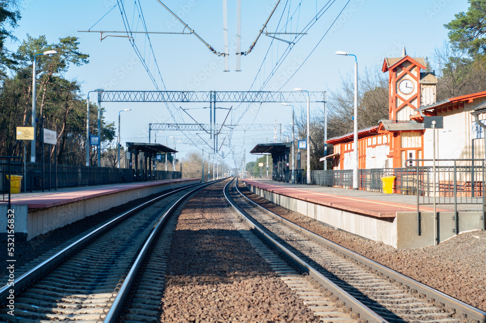 A small empty railway station, an iron track going into the distance.