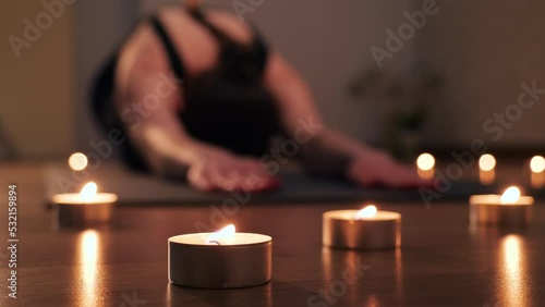 young girl in a black sports uniform practices yoga at home by candlelight