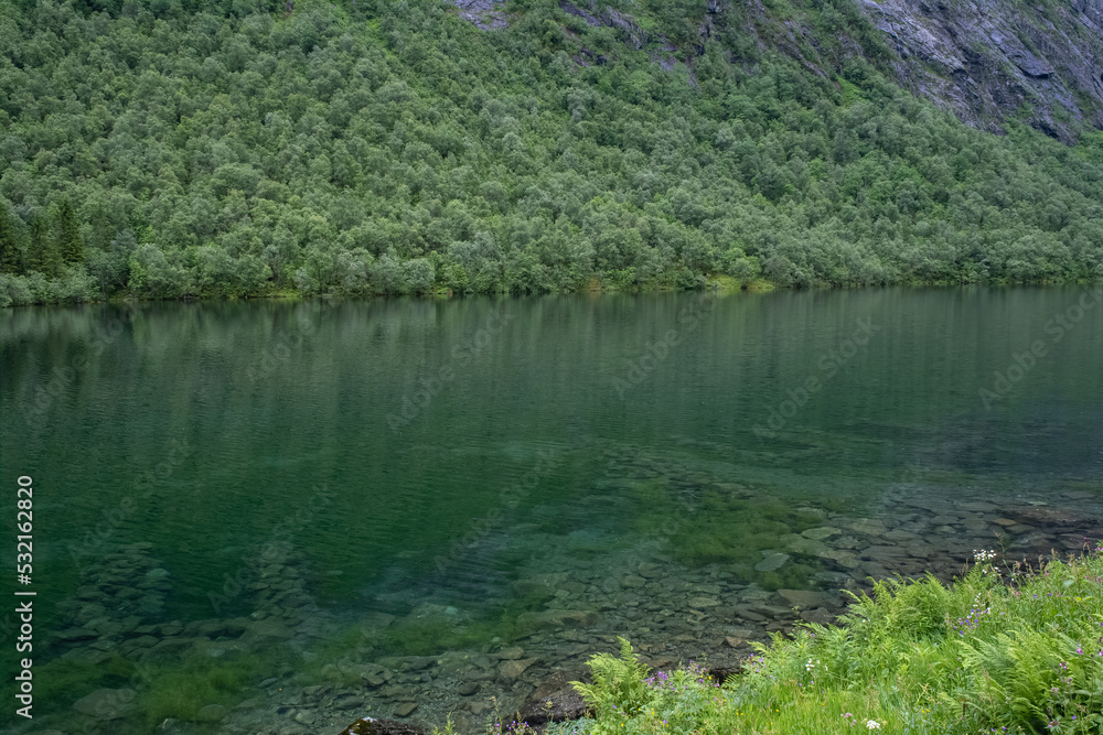 Wonderful landscapes in Norway. Vestland. Beautiful scenery of Lygnstoylvatnet lake. Remains of the flooded house foundations through the surface of the water are visible. Cloudy day. Selective focus Wonderful landscapes in Norway. Vestland. Beautiful scenery of Lygnstoylvatnet lake. Remains of the flooded house foundations through the surface of the water are visible. Cloudy day. Selective focus