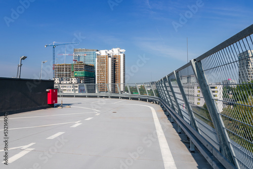 Car parking on the roof of the building. Buildings under construction in the background. Construction cranes against the background of blue sky. Katowice  Poland