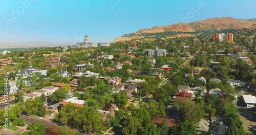 Beautiful sunny city built near the bare mountain. Magnificent State Capitol Building at the foot of rock. Salt Lake City panorama on clear summer day. photo
