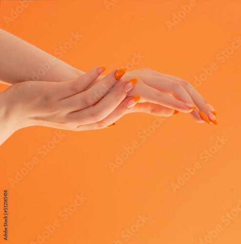 female hand with manicure on orange background