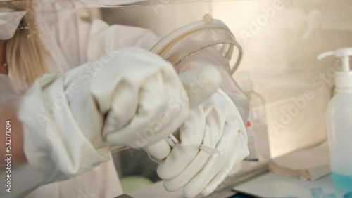 A close-up of a Covid 19 PCR testing package, handled by a trained physician, wearing heavy rubber gloves, behind a sterile booth. an NTSC video clip.
