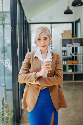 Young attractive Asian female office worker business suits smiling at camera in office .