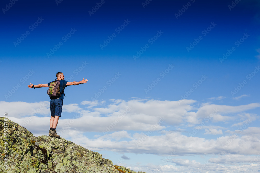 Hiker with backpack standing on top of a mountain and enjoying tne view