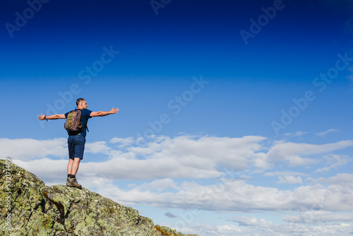Hiker with backpack standing on top of a mountain and enjoying tne view © olyphotostories