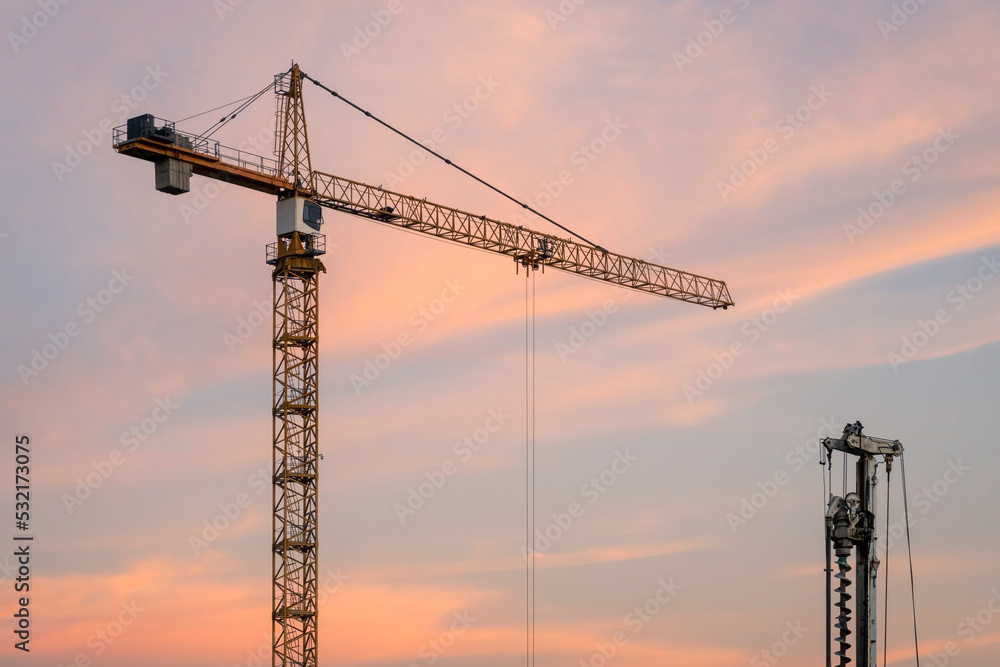 Construction equipment against sunset sky. Red tower crane Construction equipment against sunset sky. Red tower crane