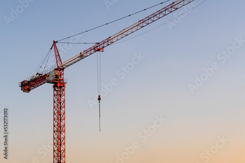 Red crane against clear sunset sky. Construction industry. Copy space for text
