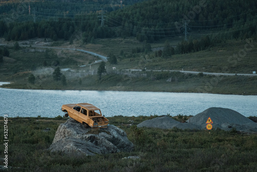 Destroyed car against the background of the lake in the mountains in Ulagan Pass in the Altai Republic