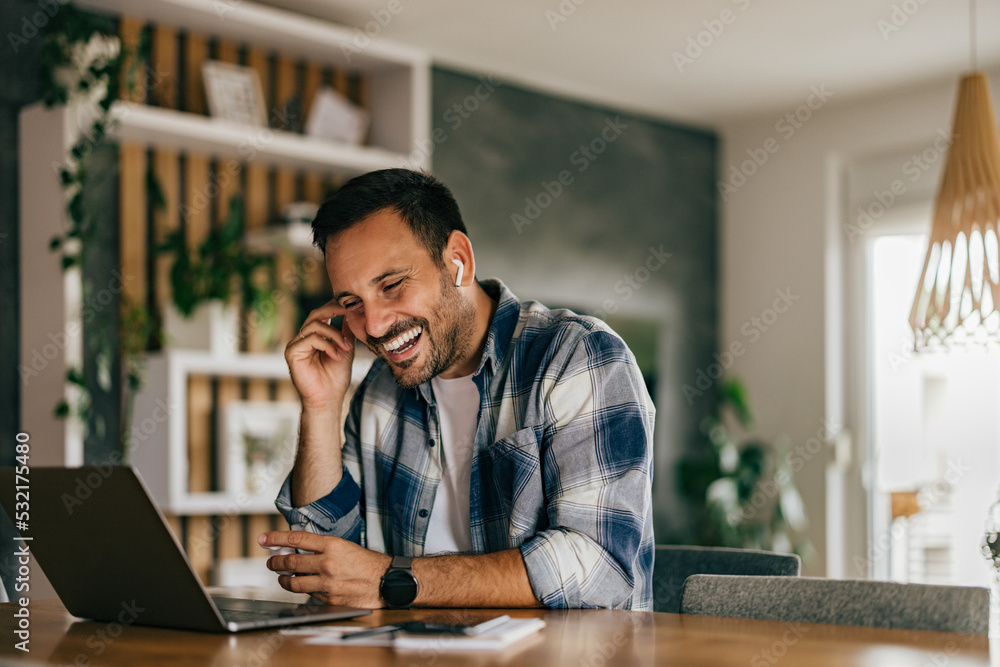 Smiling adult man having an online meeting, using a wireless ear Smiling adult man having an online meeting, using a wireless ear