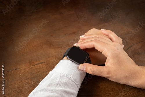 Smart watch  close up photo of woman touching smart watch. Caucasian  girl  sitting on wooden table controlling her mail  message  hearth beat  phone call  music list wearable technology concept idea.